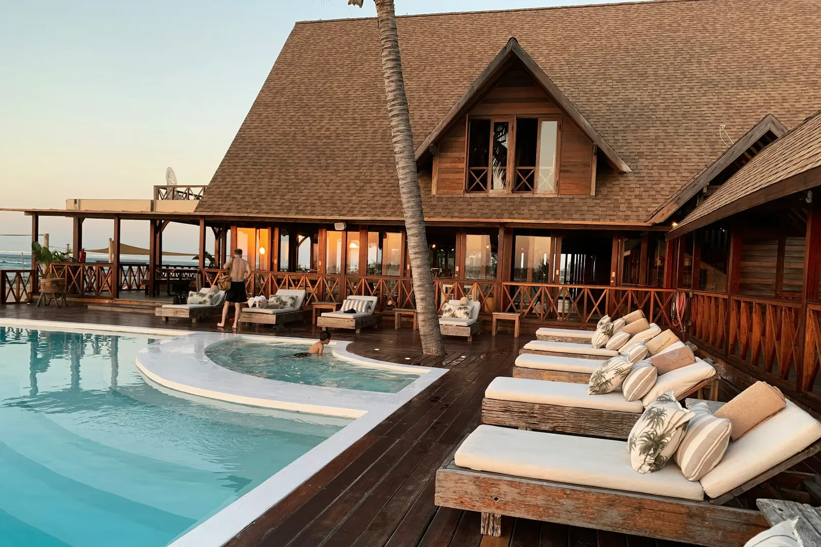 Hotel de playa con alberca y camastros al atardecer