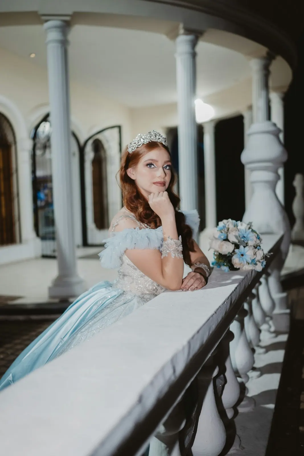 Quinceañera en un balcón con su ramo azul
