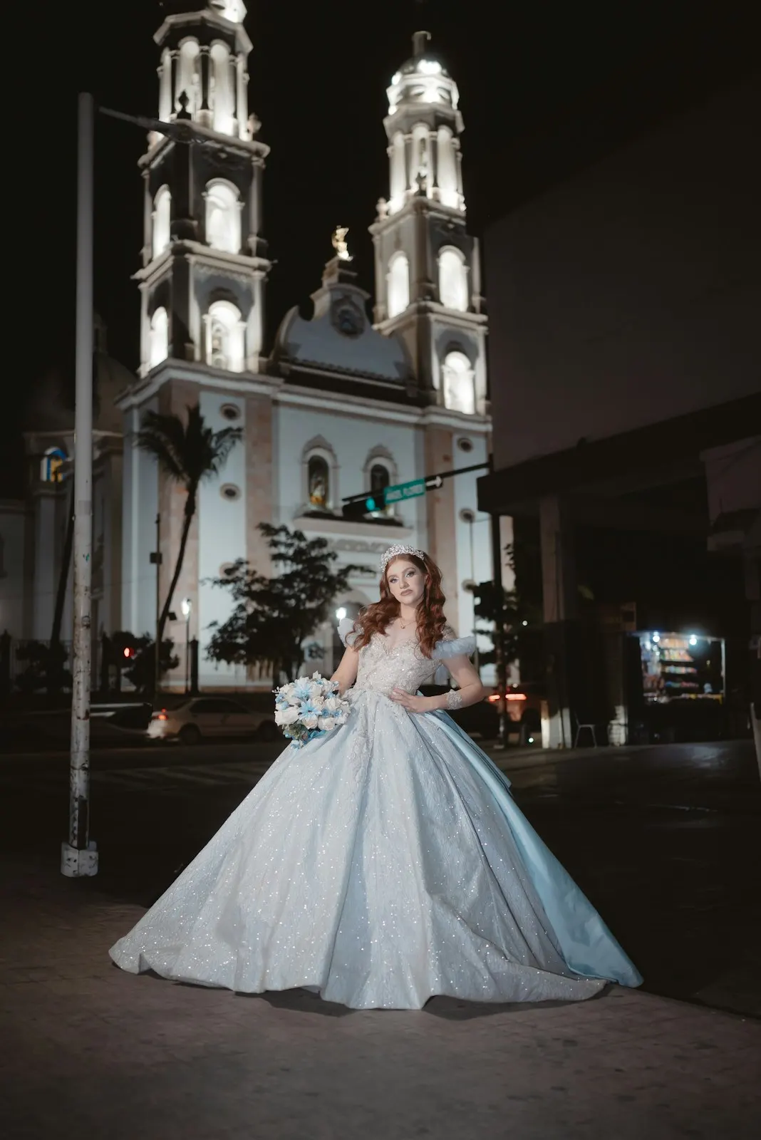 Quinceañera frente a una iglesia iluminada de noche