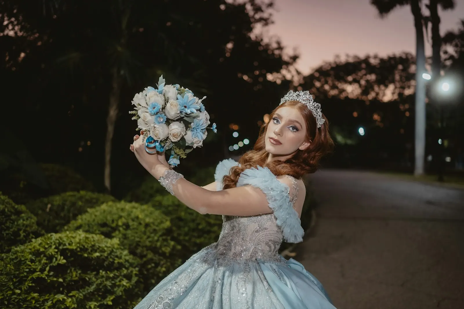Quinceañera levantando su ramo al atardecer