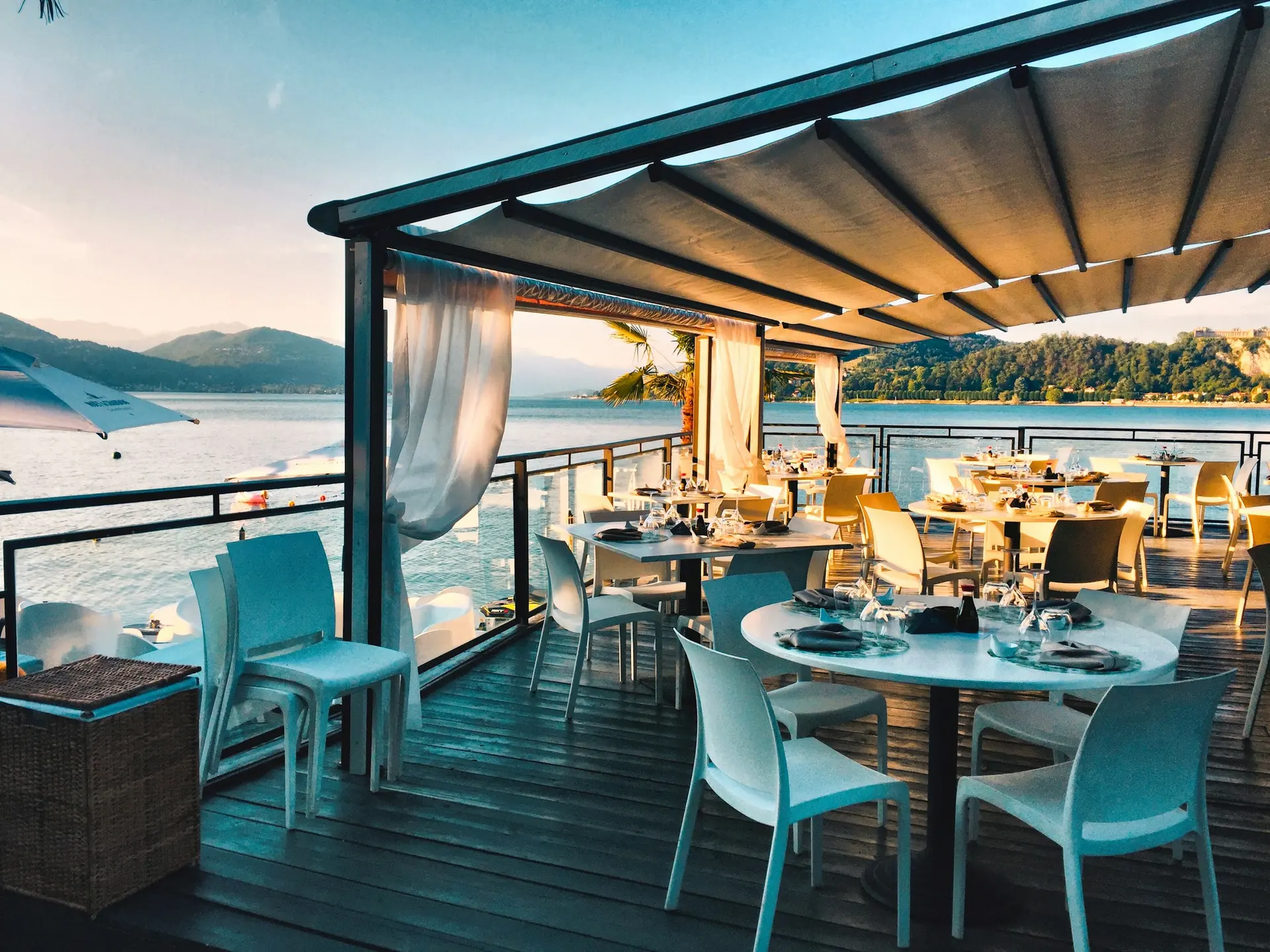 Terraza de restaurante con mesas puestas frente al mar